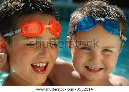 Two young boys in the pool, having tons of summer fun in matching diving goggles