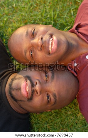 Summer portrait of two brothers lying side by side on the grass