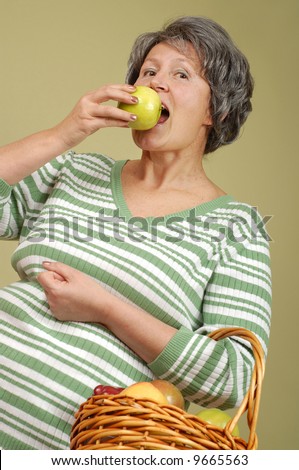 Older happy woman with a basket of delicious apples