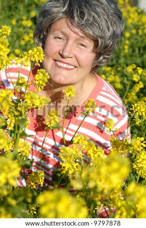 Attractive mature woman in a flower-filled spring meadow