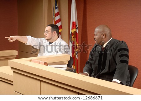 Man acting as a witness pointing out someone to the judge