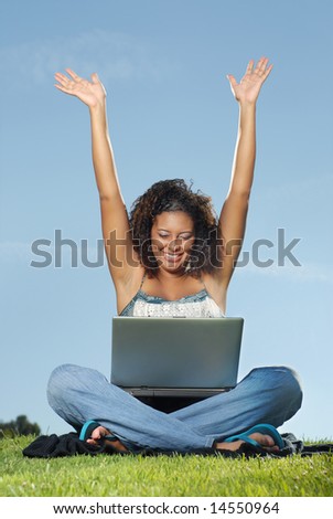 Happy student with raised arms at a laptop