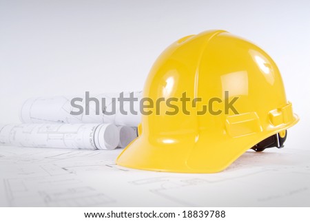 Yellow hard hat and blueprints in a construction concept