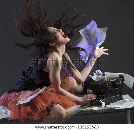 Crazy girl is sitting on the table at the typewriter