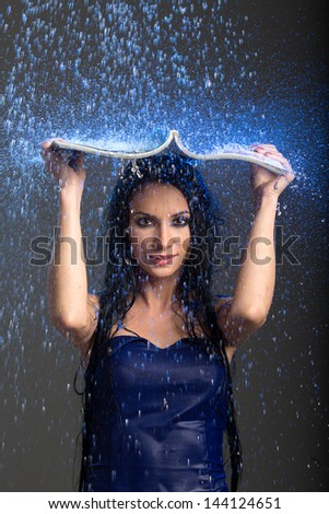 girl standing in the rain and hiding from the rain under the magazine