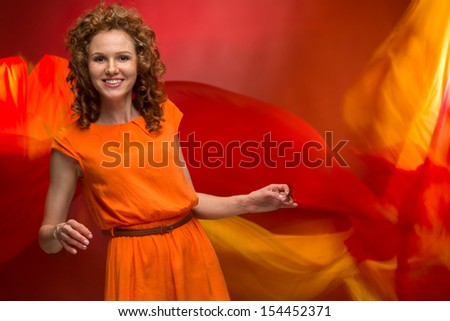 Attractive curly girl in an orange dress rings her bells