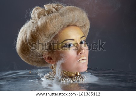 Portrait of Beautiful lady with voluminous hair style and bright make up in gold colors