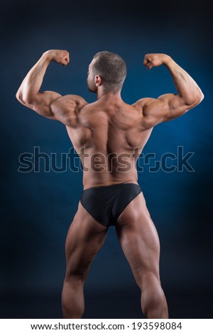 Handsome bodybuilder demonstrating his strong body and powerful back