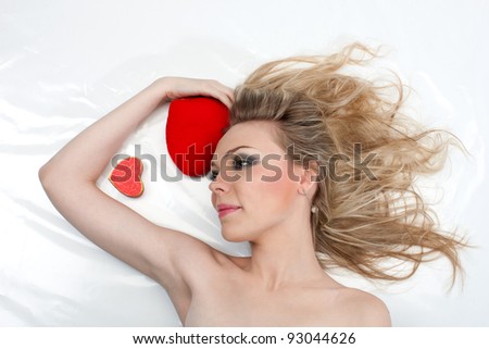 Attractive woman lying on a white background with two hearts