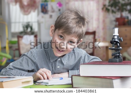 Smiling boy with school books on the table