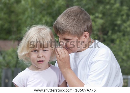 Children. The boy whispers a secret on an ear to the girl