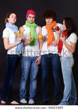 Portrait young beautiful girls and boys with fruit in studio on a dark gray background