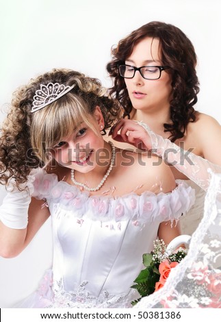The girlfriend helps the bride to dress a necklace from pearls