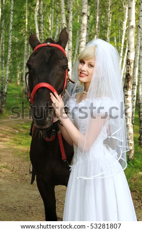 stock photo The bride in a wedding dress walks in wood with a horse