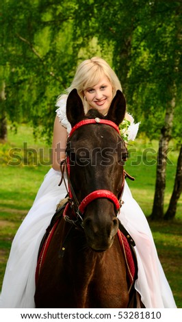 The bride in a wedding dress walks in wood with a horse