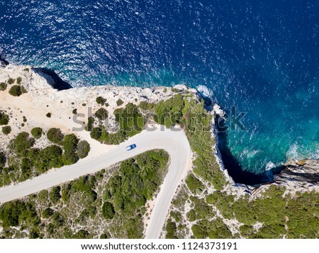 Car on coastal road meander rugged cliffs mediterranean sea