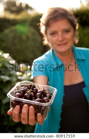 Mature woman offering Cherries.