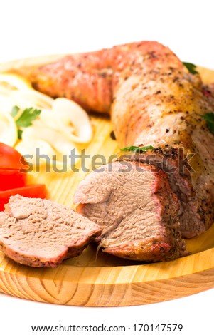 Baked pork tenderloin on wooden plate