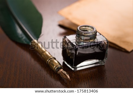 Quill pen, inkwell and paper on wooden table
