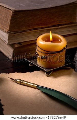 Quill pen on old paper, candle and  books