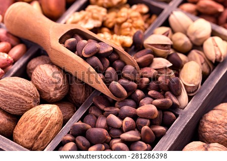 Pine nuts in scoop and other nuts in box closeup