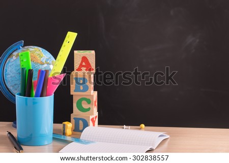 School supplies on wooden table against black board