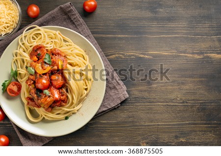 Spaghetti pasta with tomato sauce on wooden table. Top view with copy space