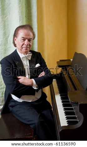 Senior man pianist.  Senior man pianist sitting next to a grand piano.