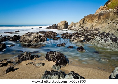 Ocean coastline landscape.  Scenic view of waves breading on rocky ocean coastline under blue skies.