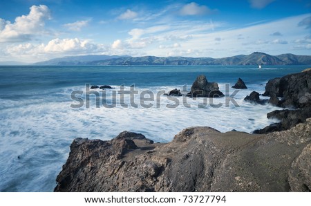 Ocean coastline landscape.  Scenic view of waves breading on rocky ocean coastline under blue skies.