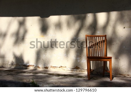 Abandoned chair against an old wall