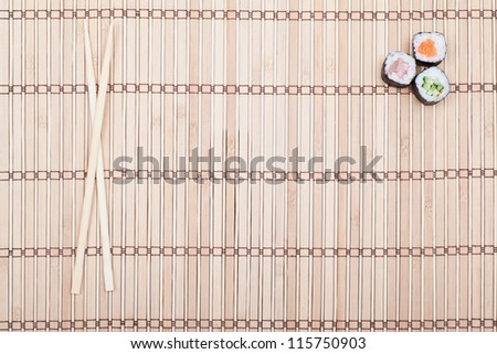 chopsticks and sushi roll on bamboo mat. background menu