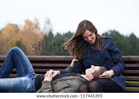 man lying in lap of young woman on park bench