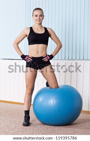 fitness woman stands with abs Swiss ball in gym