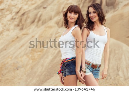 two girl holding hands on beach. outdoors woman portrait