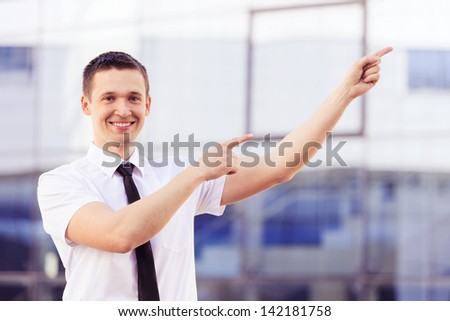 successful man pointing at side on background modern building