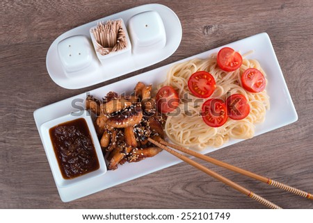 pasta with sour-sweet sauce and two chopsticks top view