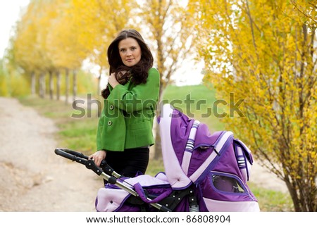 close-up happy mom with stroller in autumn city park