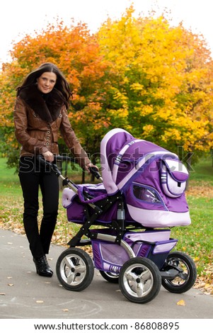 close-up young mother with stroller in autumn of city park