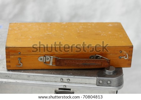 Small wooden box is powdered by snowflakes and lies on the big iron box