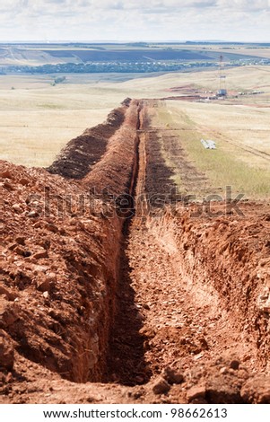 The trench for laying oil pipes in the oil field in Russia