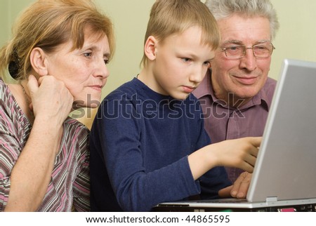 grandfather and grandmother with her grandson play in a notebook