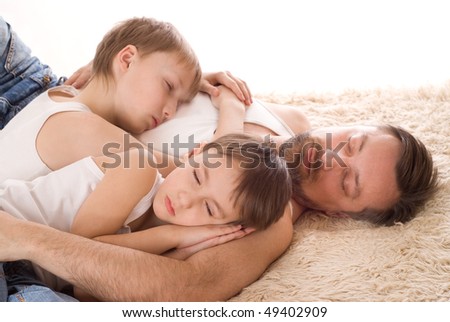 young father with his two sons sleep on the bed