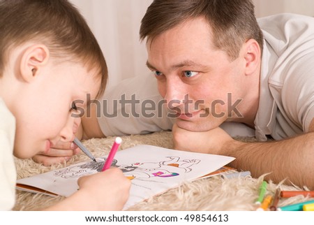 Father and son lying on the carpet, and paint