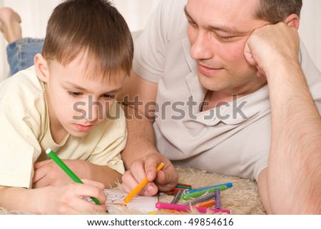 Father and son lying on the carpet and fight on his hands