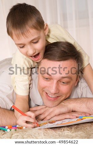 Father and son lying on the carpet, and paint