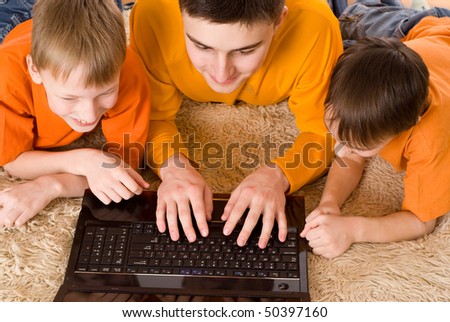 three brothers played happily on the laptop in orange shirts