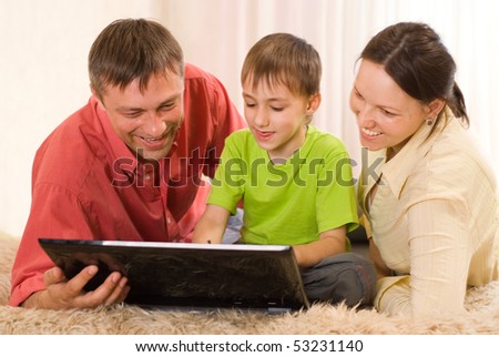 family lying on the carpet with a laptop