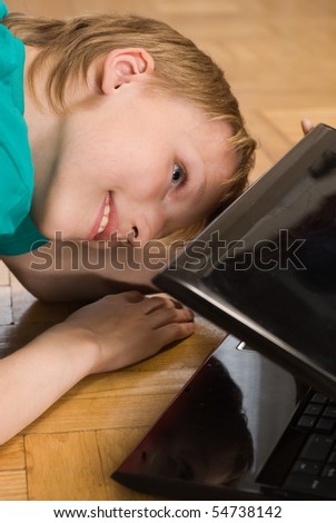 boy on the floor peering into a laptop