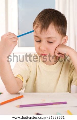 boy with a pencil sitting at the table and draws